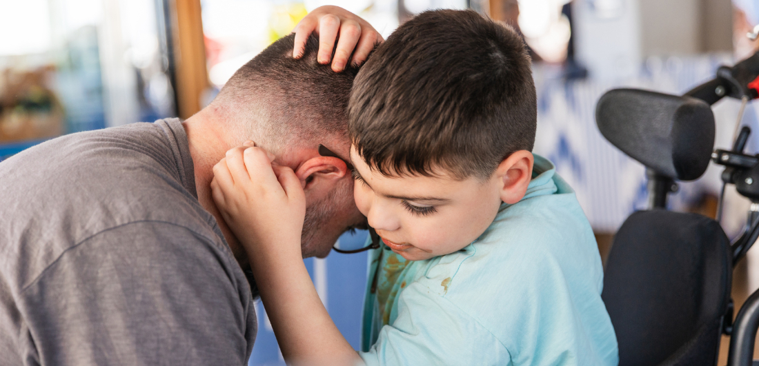Dad and son (in wheelchair) cuddling