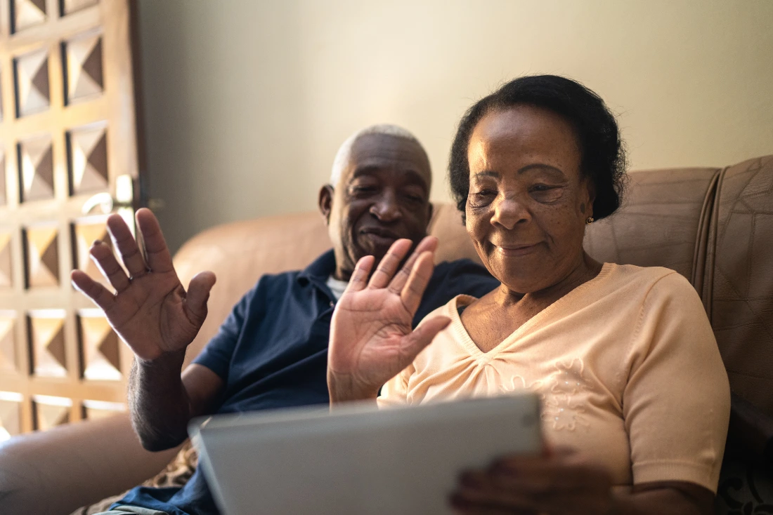 A couple waving at an Ipad screen as though on a video call