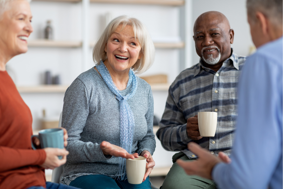 Four people talking with mugs of coffee